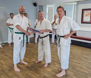 Neil receiving his blue belt from two instructors